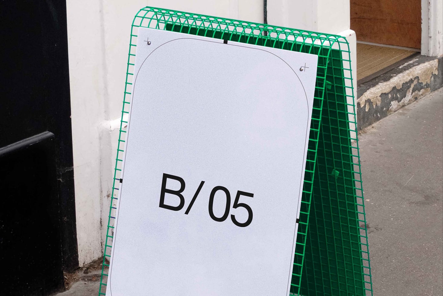Green plastic A-frame sidewalk sign with white display surface showing B/05 text