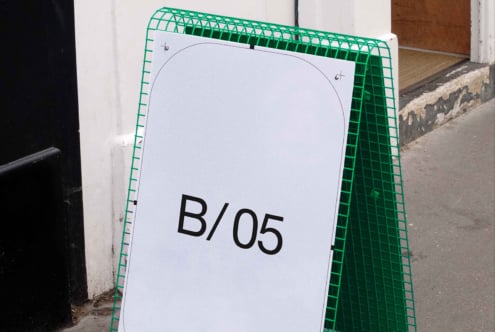 Green plastic A-frame sidewalk sign with white display surface showing B/05 text