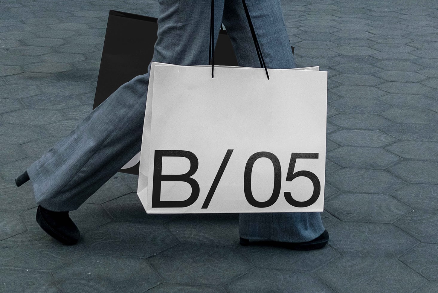 White shopper bag mockup being carried with B/05 text displayed