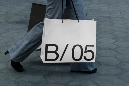 White shopper bag mockup being carried with B/05 text displayed