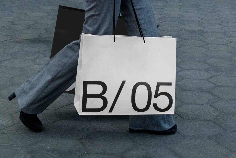 White shopper bag mockup being carried with B/05 text displayed