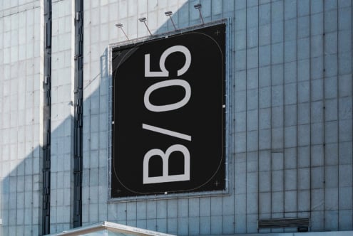 Large outdoor billboard mounted on glass building showing B/05 in white letters