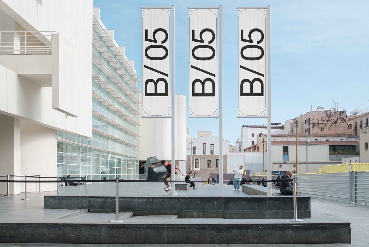 Three tall vertical banners on building facade overlooking plaza, text B/05