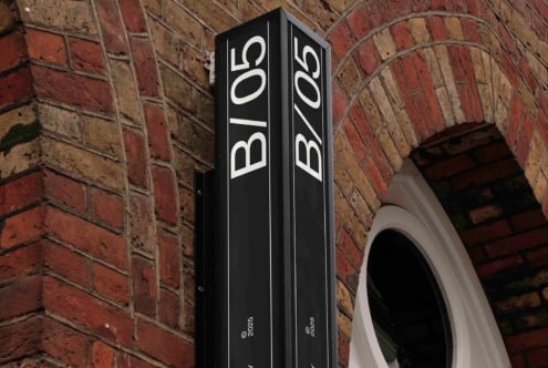 Black vertical signage with B05 in white letters mounted on brick building corner