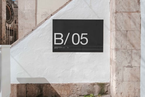 Dark horizontal sign mockup with B/05 text on weathered whitewashed stone wall
