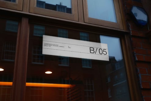 Horizontal storefront sign with B/05 text on wood building with orange neon trim