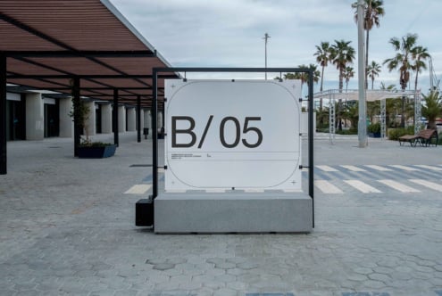 White outdoor billboard mockup on concrete plaza with palm trees in background