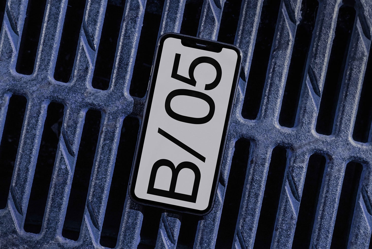 Phone displaying bold B/05 typography on light background against blue metal ridges
