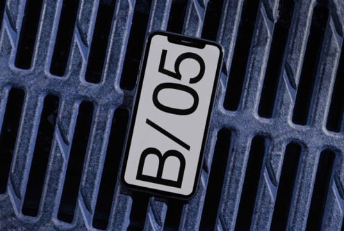 Phone displaying bold B/05 typography on light background against blue metal ridges