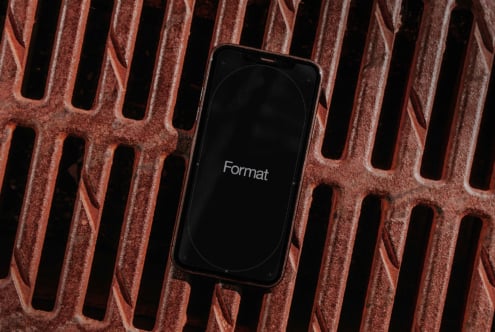 iPhone on rust-colored textured metal grate with Format text on screen