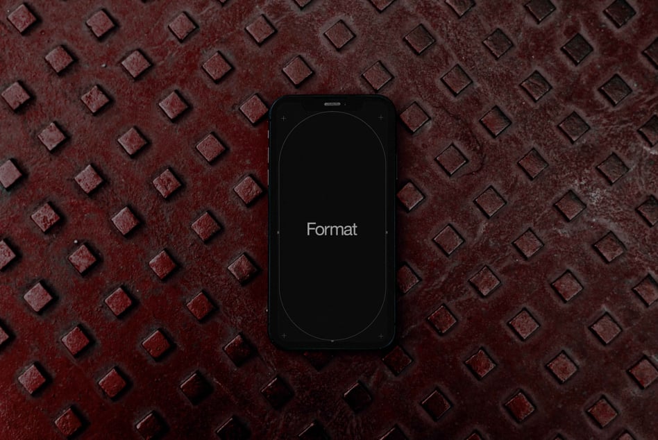 Black smartphone on textured red diamond plate surface, dark screen