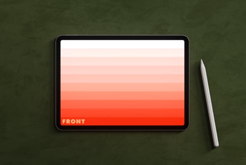 Tablet on green surface displaying coral gradient with stylus pen nearby