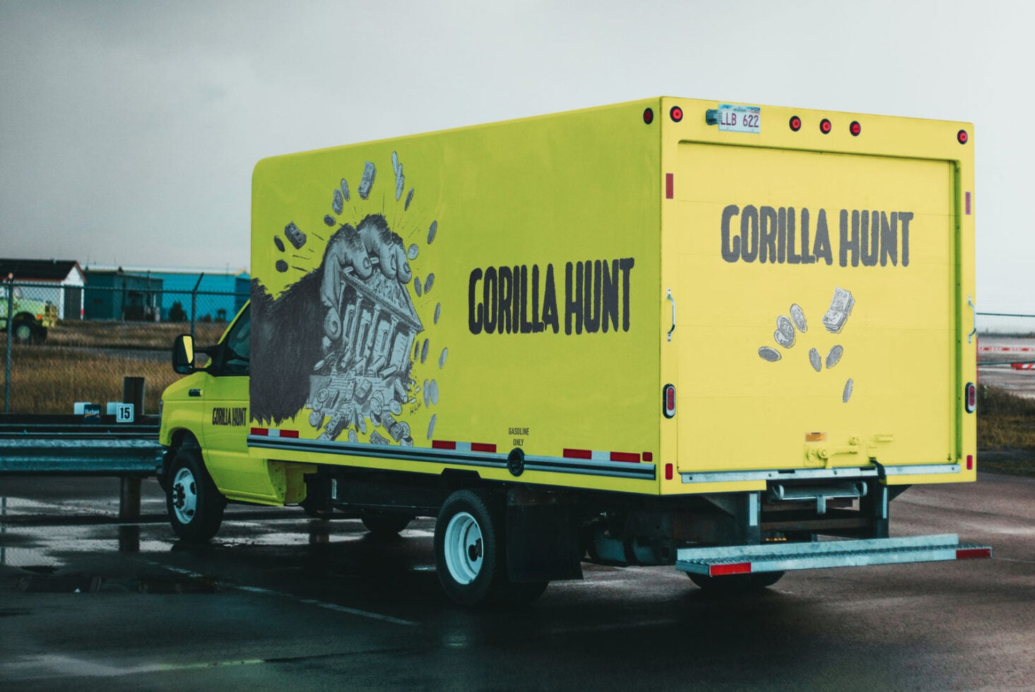 Neon yellow delivery truck mockup with gorilla hunt branding at industrial lot