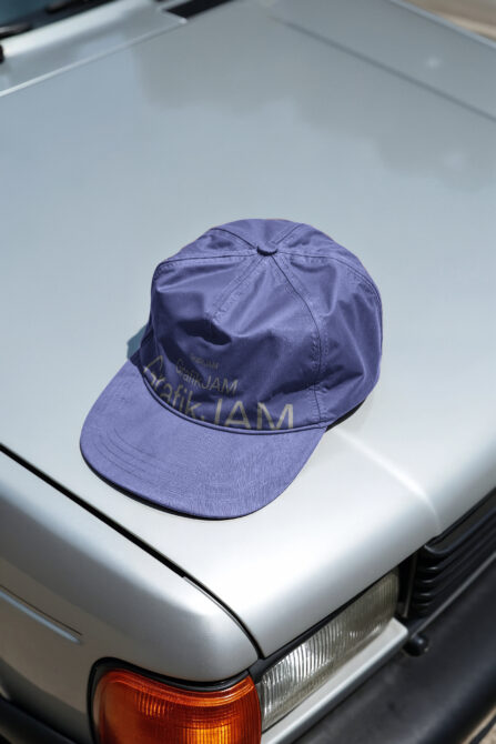 Purple baseball cap with embroidered branding on white car hood