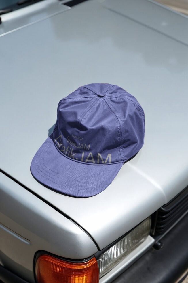 Purple baseball cap with embroidered branding on white car hood