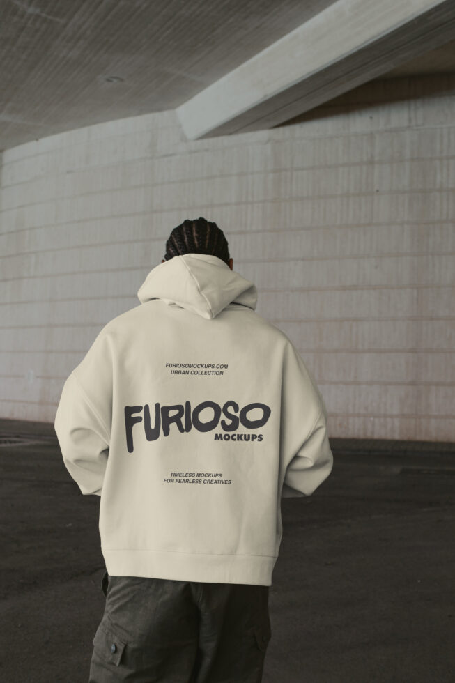 Cream hoodie back view, minimal urban setting with concrete ceiling