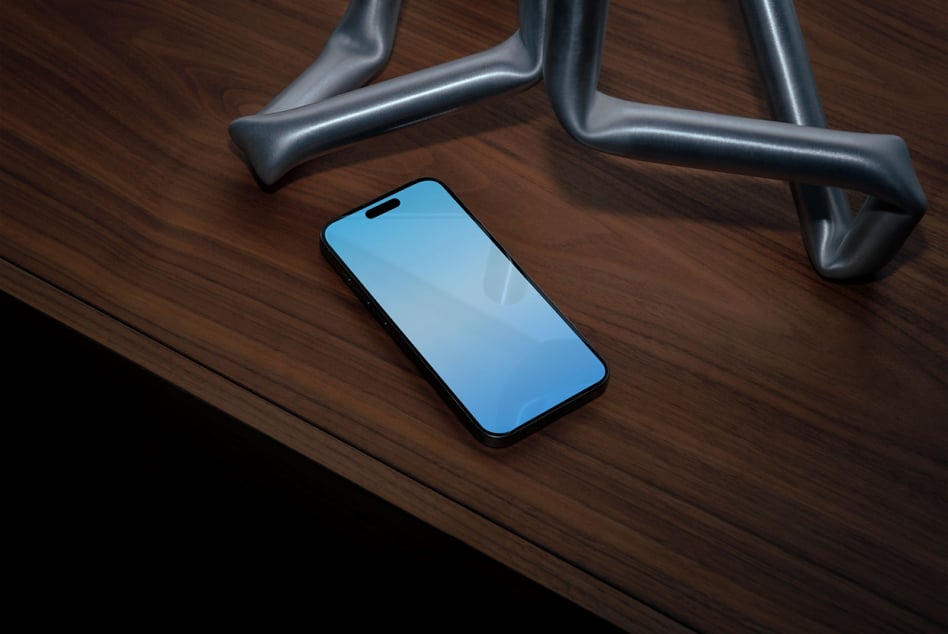 iPhone mockup with bright blue screen on desk with metal chair legs, wood surface