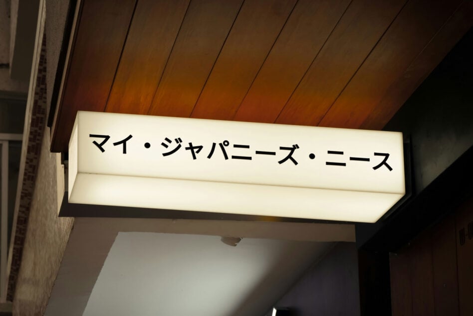 Lit ceiling sign with Japanese characters on wooden paneled background