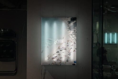 Aerial beach poster with cursive script on white lit display wall