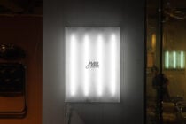 White neon glowing script on illuminated poster mounted indoors