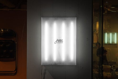 White neon glowing script on illuminated poster mounted indoors