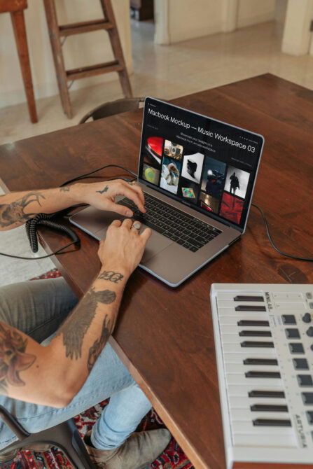 Macbook Pro on wooden desk showing music workspace mockup with keyboard, coiled cable nearby