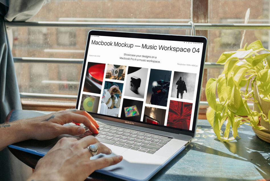 Person working on Macbook Pro showing music workspace mockup near potted plant by brick window