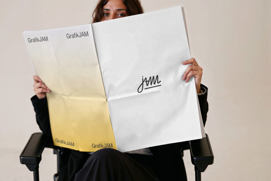 Person flipping open brochure showing yellow gradient, white spread, handwritten logo