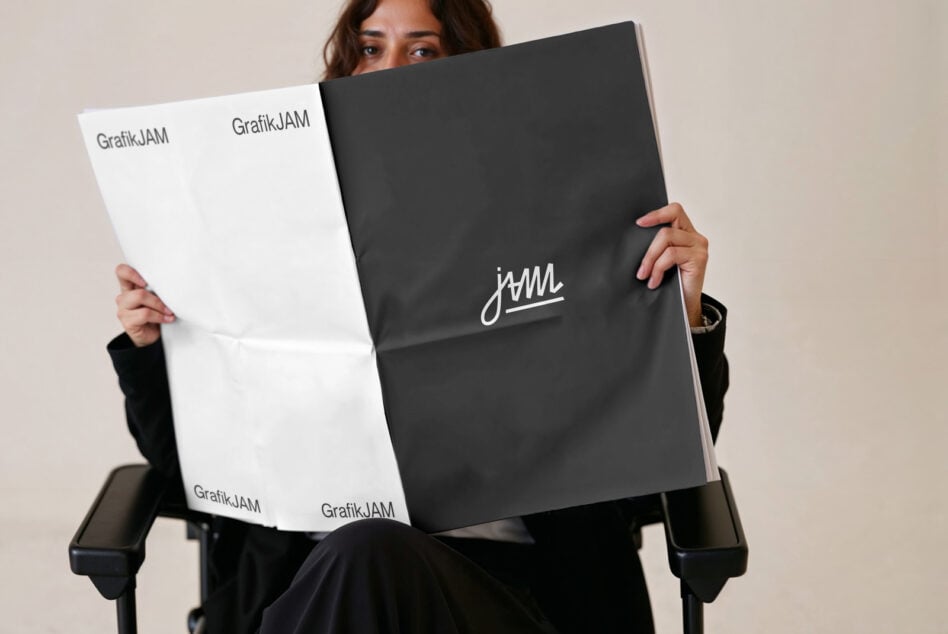 Woman holding open brochure with white left, black right page, centered cursive mark