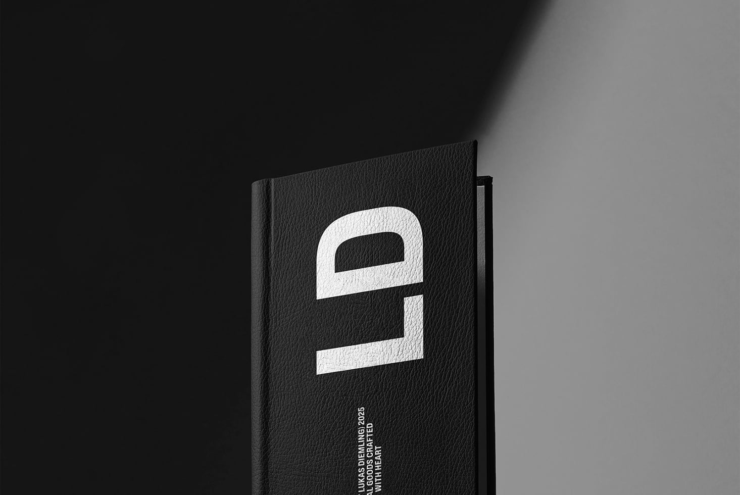 Black hardcover book angled showing white geometric logo design