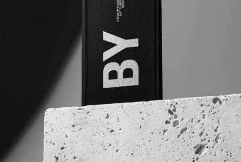 Black hardcover book with white geometric logo on concrete surface