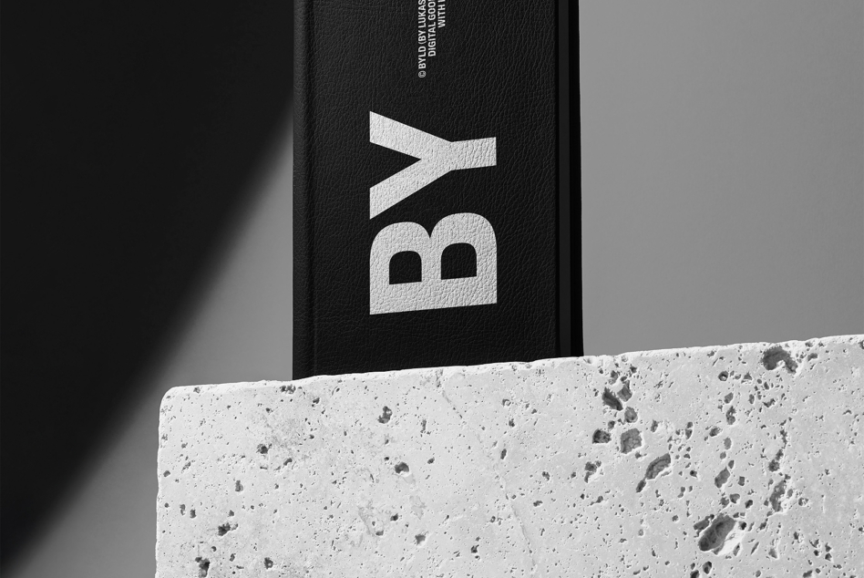 Black hardcover book with white geometric logo on concrete surface