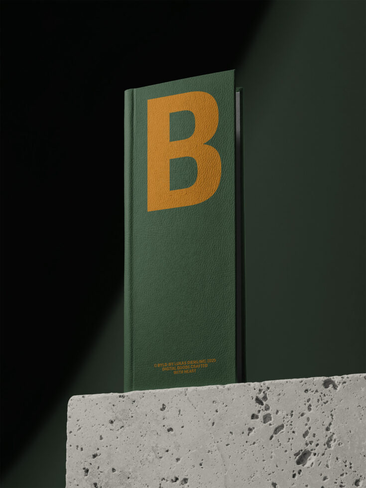 Green cloth hardcover book on concrete block featuring large gold letter B logo