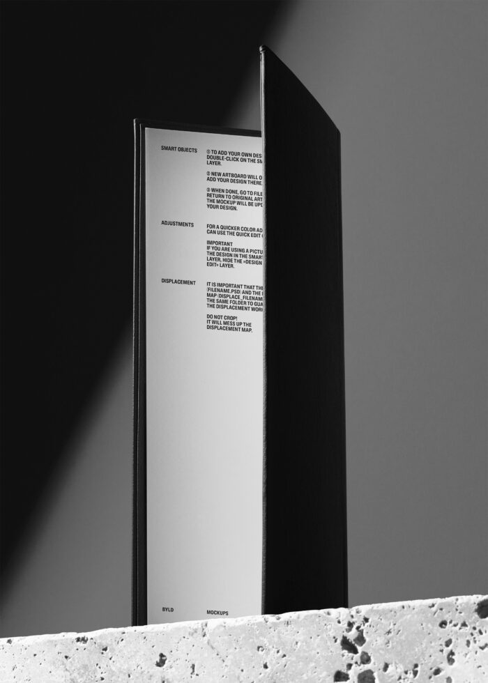 Black hardcover book standing open against gray background with instruction text