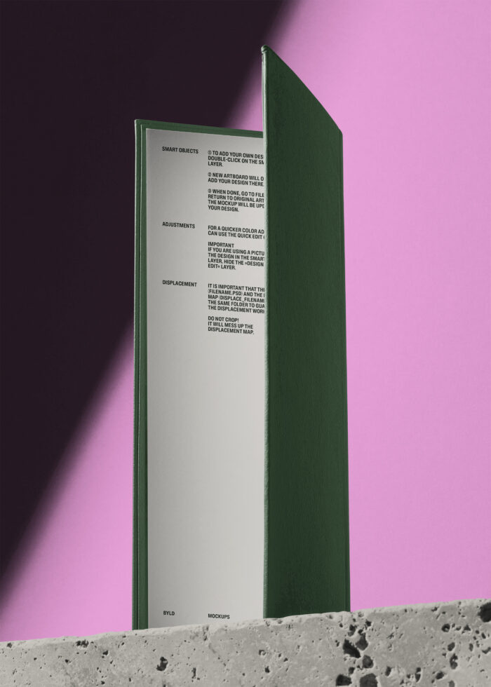 Green hardcover book standing open against pink background with instructions page visible