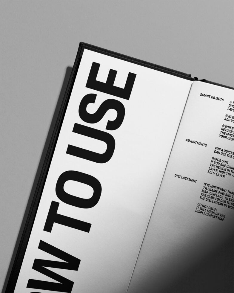 Open hardcover book with black spine on gray background showing interior pages