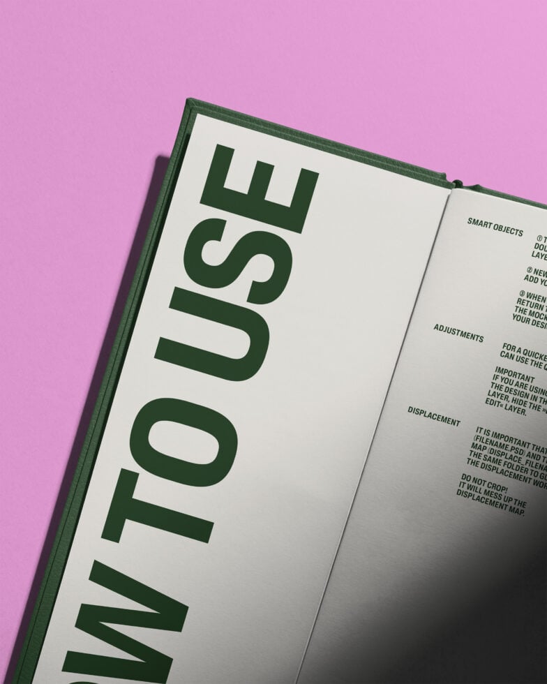 Open hardcover book with green spine on pink background showing interior pages