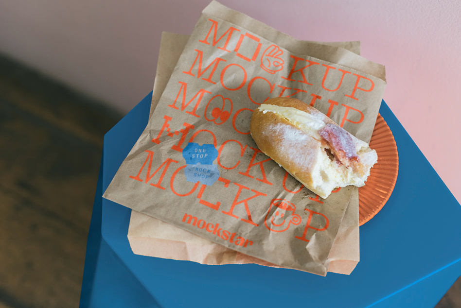 Kraft paper bag with red MOCKUP text printed on it holding sandwich on blue box