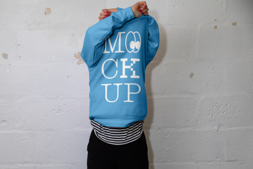 Person from behind wearing bright blue hoodie with white MOCK UP text on back