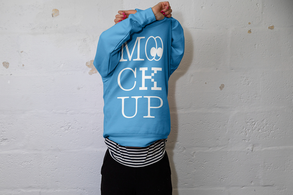 Person from behind wearing bright blue hoodie with white MOCK UP text on back