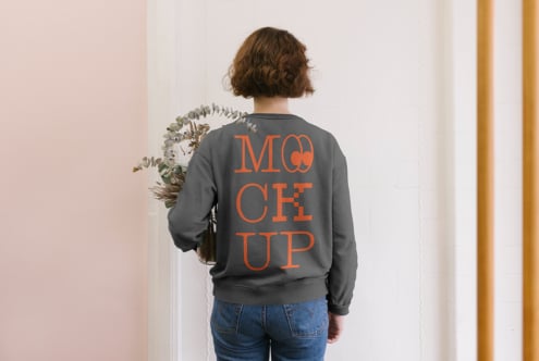 Back view of woman in charcoal sweatshirt with orange MOCK UP text holding eucalyptus