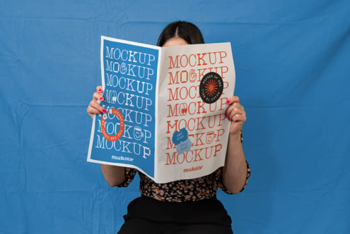 Woman holding open magazine mockup with blue cover, stickers visible
