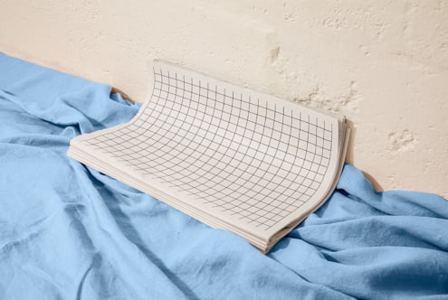 Grid notebook mockup draped over rumpled blue linen fabric