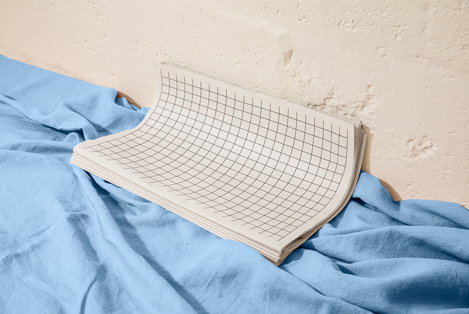Grid notebook mockup draped over rumpled blue linen fabric