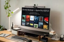 Dark background monitor mockup on desk with camera, keyboard, mug setup