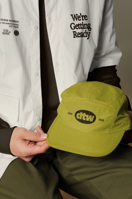 Person holding lime green snapback cap with dtw logo, white shirt visible