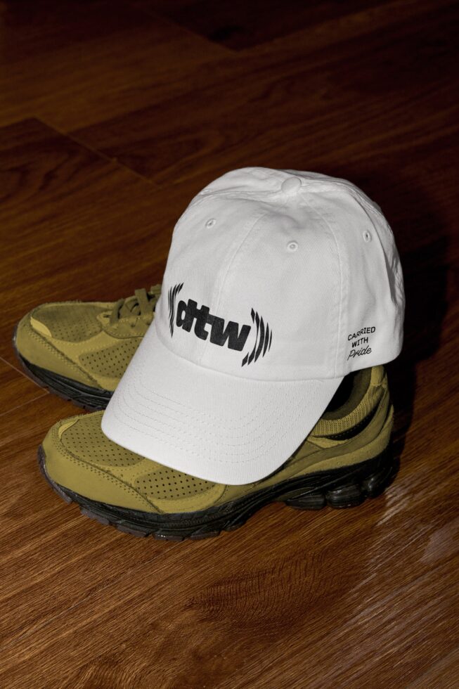 White cap with ohtwn logo on tan hiking boots wooden floor