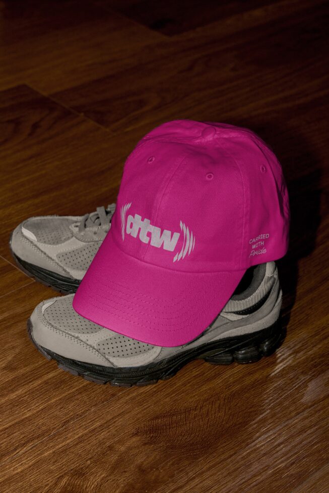 Bright magenta pink cap with white atw sound wave logo worn on sneaker display setup