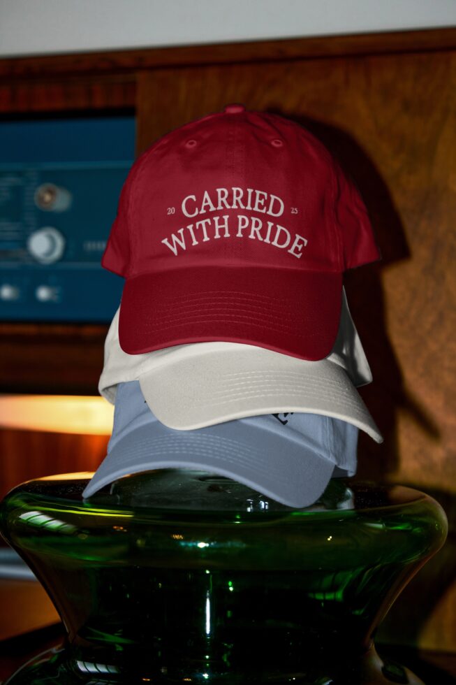Burgundy red white light blue baseball caps stacked showing 'carried with pride' embroidered text