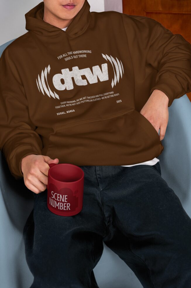Brown hoodie mockup with white graphic print on chest, holding red mug
